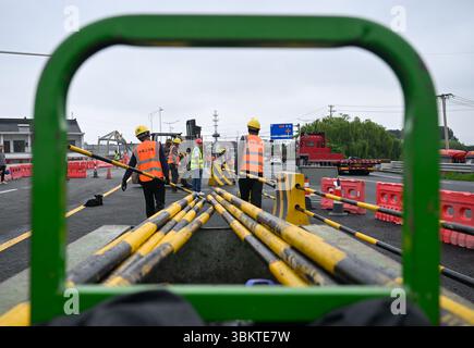 Suzhou. 23 juin 2025. Les ouvriers ont remis en place les séparateurs routiers pour les voies de gauche du pont de Pingwang nouvellement construit dans le district de Wujiang de la ville de Suzhou, dans la province du Jiangsu de l'est de la Chine, le 23 juin 2025. Les voies de gauche du pont de Pingwang nouvellement construit, un projet de la partie est du projet d'amélioration du canal de navigation de Chang-Hu-Shen (Changxin-Huzhou-Shanghai) (section Jiangsu), ont été officiellement ouvertes à la circulation lundi. Crédit : Ji Chunpeng/Xinhua/Alamy Live News Banque D'Images