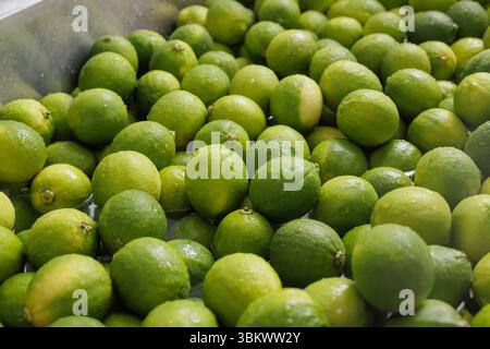 Gros plan de limes vertes fraîches lavées à l'eau pour une utilisation dans l'industrie alimentaire commerciale, parfait pour une alimentation saine et la production de boissons Banque D'Images
