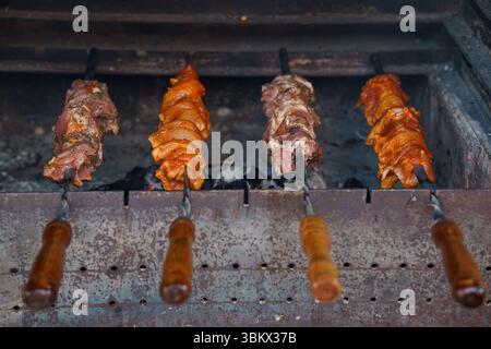 Scène churrasco brésilienne authentique avec des brochettes de viandes assaisonnées rôties sur charbon de bois chaud, un barbecue gaucho classique avec rouge et brun riches Banque D'Images