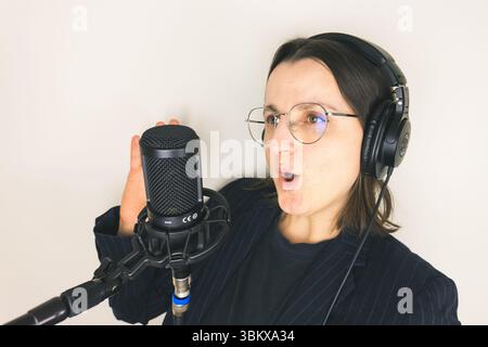 Jeune femme caucasienne chantant dans le microphone portant des écouteurs. Banque D'Images
