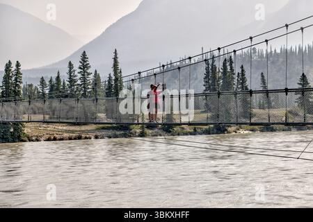 Une mère et son fils debout sur la passerelle qui enjambe la rivière Sakatchewan Sud menant aux chutes Siffleur dans la réserve écologique des plaines Kootenay Banque D'Images