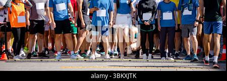 Grand groupe de coureurs, athlètes à la ligne de départ quelques secondes avant le début de leur course, dans une compétition de marathon de rue, foule de gens en attente de course Banque D'Images