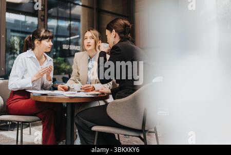 Trois femmes d'affaires ayant une conversation autour d'un café lors d'une réunion dans un bureau moderne Banque D'Images