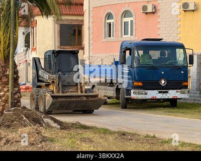 Chargeur compact rigide déversant du sol dans le tombereau sur un chantier urbain Banque D'Images