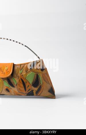 Sac à main orange fait à la main sur un fond blanc, sac à main en cuir orange fait à la main, sac à main artisanal en or orange avec une poignée courte en chaîne Banque D'Images