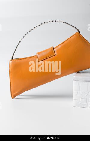 Sac à main orange fait à la main sur un fond blanc, sac à main en cuir orange fait à la main, sac à main artisanal en or orange avec une poignée courte en chaîne Banque D'Images