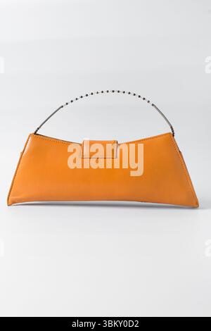 Sac à main orange fait à la main sur un fond blanc, sac à main en cuir orange fait à la main, sac à main artisanal en or orange avec une poignée courte en chaîne Banque D'Images