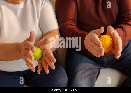 Couple de personnes âgées utilisant des balles de massage spiky pour l'exercice de la main soulagement de la douleur, réhabilitation et soutien de bien-être à la maison Banque D'Images