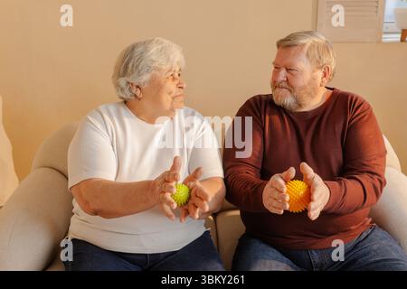 Couple de personnes âgées utilisant des balles de massothérapie spiky pour le soulagement de la douleur de réhabilitation d'exercice de la main et le soutien de bien-être à la maison Banque D'Images