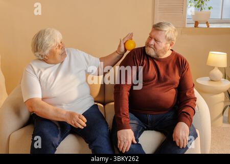 Couple de personnes âgées utilisant une boule de thérapie de massage spiky pour soulager le mal de dos récupération musculaire et soutien de bien-être à la maison Banque D'Images