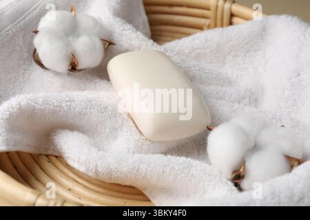 Pain de savon, serviette et fleurs de coton dans un panier en osier, gros plan Banque D'Images