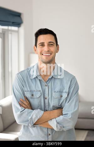Heureux jeune homme debout au salon dans la pose confiante Banque D'Images