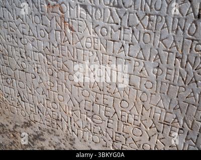 Un gros plan révèle une ancienne tablette de pierre ornée d'inscriptions grecques profondément sculptées, mettant en valeur l'importance historique et l'héritage durable de la civilisation grecque antique. Banque D'Images
