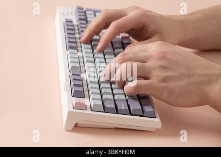 Main Mans tapant sur le clavier mécanique sur le bureau rose. Gros plan. Banque D'Images