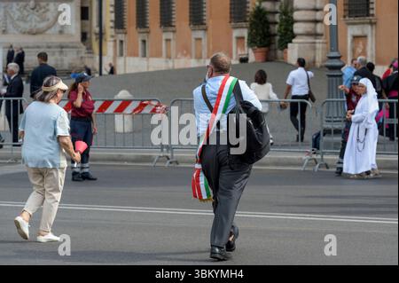 Rome, Italie. 22 juin 2025. Un maire venu à Rome pour le Jubilé des gouverneurs arrive rapidement à son siège où il suivra la messe à l’occasion de la célébration du Corpus Christi présidée par le Pape Léon XIV à Rome. Signifie littéralement « corps du Seigneur », c'est l'une des principales solennités de l'année liturgique de l'Église catholique au cours de laquelle est célébré le Sacrement de l'Eucharistie, la consécration de la présence du Christ dans les croyants. Dans ce Sacrement, l'Église trouve la source de son existence et de sa communion avec le Christ, présent dans l'Eucharistie en corps, Banque D'Images