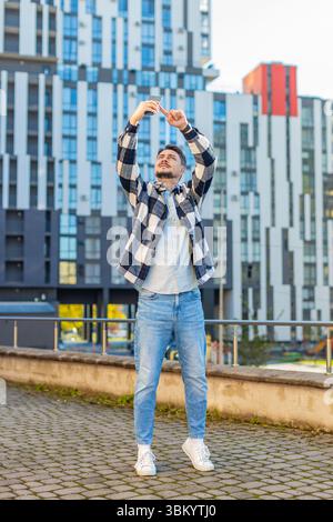 Homme d'âge moyen touriste essayant d'attraper un signal de communication et Internet sur le téléphone mobile, a soulevé le téléphone pour une meilleure connexion dans la rue du centre-ville. Un caucasien frustré en ville. Banque D'Images