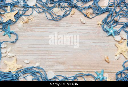 Filet de pêche bleu avec étoiles de mer et coquillages créant un cadre sur un fond en bois rustique, idéal pour les vacances d'été et les thèmes de bord de mer Banque D'Images