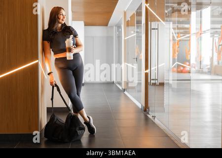 Portrait pleine longueur de femme sportive de taille plus en vêtements d'action avec sac de gymnastique à l'intérieur du studio Banque D'Images