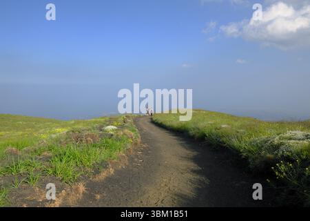 Sentier panoramique avec deux randonneurs à distance à l'horizon sous le ciel bleu dans Etna Park, Sicile, Italie (2) Banque D'Images