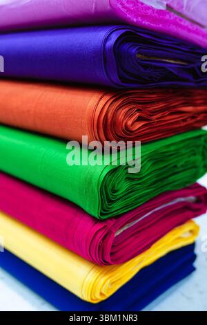 Vue rapprochée d'une pile de tissus roulés présentant une variété de couleurs riches, y compris violet, bleu, orange, vert, rose, jaune et bleu. L'ambiance Banque D'Images