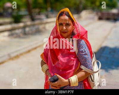 Inde, Delhi, 25 juin 2025. Portrait d'une femme locale en tenue traditionnelle colorée, debout dans une rue ensoleillée à Paharganj. Banque D'Images