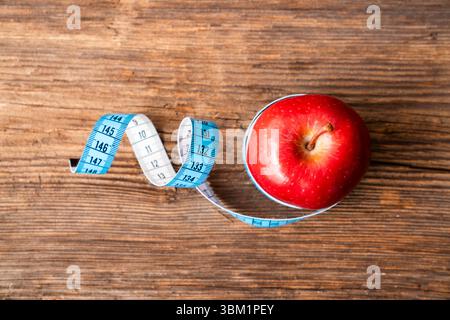 pomme rouge isolée enveloppée de ruban de mesure sur fond blanc. Régime alimentaire et concept de vie saine Banque D'Images