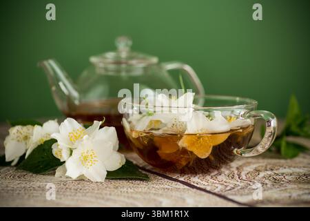 Fleurs de jasmin et thé dans une tasse sur un fond vert. Banque D'Images