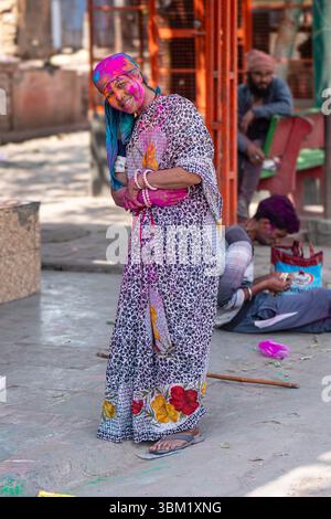Inde, Jaipur, 22 mars 2025. Une femme âgée en sari traditionnel, le visage couvert de poudres colorées, célèbre le festival Holi à Jaipur Banque D'Images