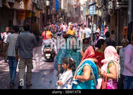 Inde, Jaipur, 22 mars 2025. Scène de rue colorée pendant le festival Holi à Jaipur, avec des gens couverts de poudre, de motos et de pousse-pousse sur un bustli Banque D'Images
