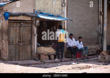 Inde, Jaipur, 22 mars 2025. Scène de rue locale à Jaipur : petit stand en bord de route vendant des marchandises tandis que les hommes s'assoient et discutent sur le trottoir. Vie quotidienne Banque D'Images