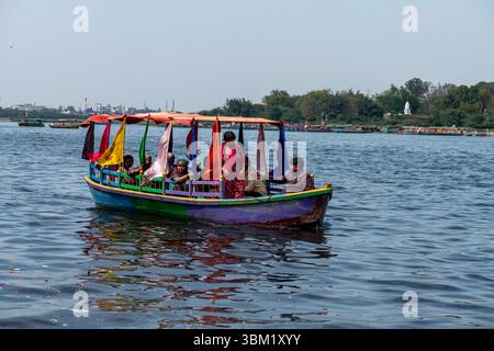 Inde, Jaipur, 22 mars 2025. Bateau coloré transportant des passagers sur un lac à Jaipur. Promenade traditionnelle en bateau en bois pendant la saison des festivals Holi. Banque D'Images
