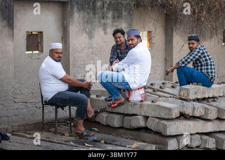 Inde, Jaipur, 22 mars 2025. Groupe d'hommes se détendre et discuter dans une cour urbaine à Jaipur. Photographie de rue franche capturant la vie quotidienne. Banque D'Images
