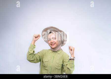 Excité. Portrait d'une jeune femme asiatique portant le hijab et porter un chapeau de plage à Copy Space Advertising Your Text, debout isolé au-dessus du blanc Studio bac Banque D'Images