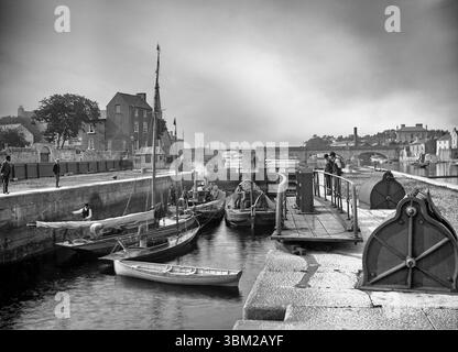 Photographie du début du XXe siècle de barges et de yachts dans l'écluse, située sur la rive ouest de la rivière Shannon à Athlone, comté de Roscommon, Irlande. Ils sont situés à côté de la maison d'un gardien d'écluse/maître de port associé, qui fait partie des travaux de navigation de Shannon, qui ont eu lieu entre 1840-9 dans le but d'ouvrir le Shannon à un trafic commercial et commercial accru. Banque D'Images