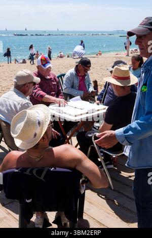 Hommes jouant aux dominos le long de la plage de nova icaria, Barcelone, Espagne. Banque D'Images