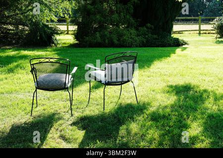 Deux chaises vides dans un jardin éclairé par le soleil du soir Banque D'Images