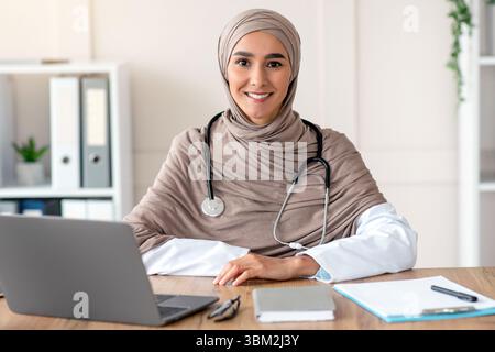 Portrait d'une femme médecin souriante assise au bureau de la clinique Banque D'Images