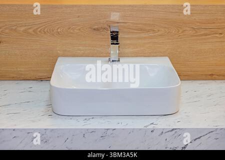 Lavabo en céramique avec robinet en argent robinet d'eau Marble Top mur en bois dans la salle de bains moderne Banque D'Images
