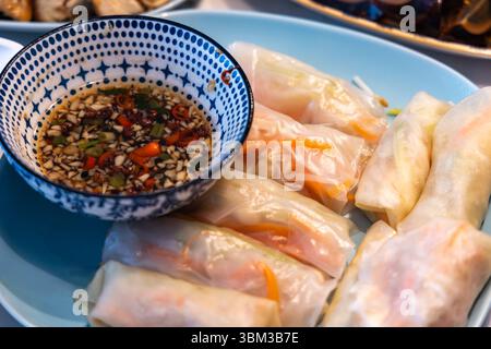 Rouleau de printemps alimentaire traditonal asiatique avec un bol de trempette sur la table - gros plan Banque D'Images