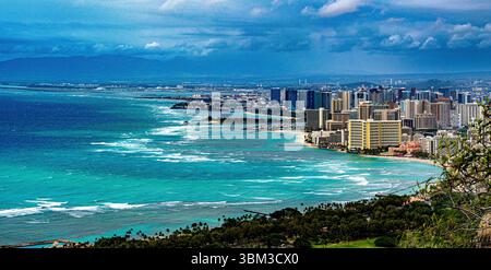 Vue aérienne de la magnifique côte d'Honolulu, où les eaux turquoises rencontrent les plages de sable et les gratte-ciel de la ville, encadrés par des montagnes luxuriantes Banque D'Images