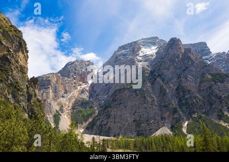 Vue imprenable sur le pic Seekofel depuis le lac Braies, mettant en valeur ses pentes rocheuses accidentées et ses parcelles de neige au milieu des forêts de pins dans les Dolomites, Ita Banque D'Images