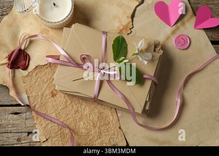 Pile de lettres d'amour, fleur, coeurs en papier, bougie et feuilles de parchemin sur la table en bois, pose à plat Banque D'Images