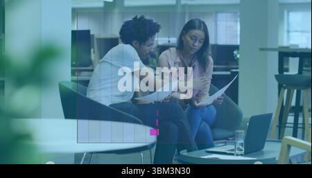 Examen de documents imprimés, deux professionnels collaborant dans des chaises longues de bureau, avec ordinateur portable Banque D'Images