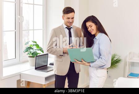 Heureux souriant divers employés de bureau coopérant sur le projet avec ordinateur portable, regardant l'écran Banque D'Images