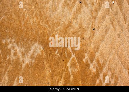 Gros plan de sable sur le rivage formant différentes textures géométriques colorées en jaune au Maroc Banque D'Images