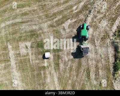 Un tracteur avec une presse dans le champ, tiré avec un drone Banque D'Images