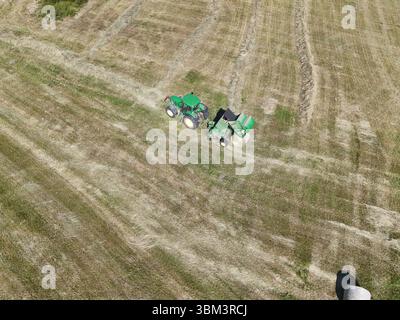 Un tracteur avec une presse dans le champ, tiré avec un drone Banque D'Images