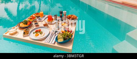Matinée tropicale relaxante avec petit déjeuner flottant dans la piscine à débordement au complexe de luxe, fruits exotiques, œufs, jus servis moment de vacances pittoresque au bord de la piscine Banque D'Images