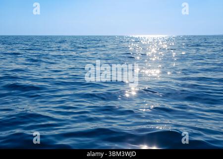 La mer bleue calme scintille avec des reflets du soleil créant un chemin de lumière à la surface de l'eau Banque D'Images