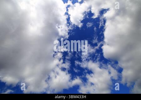 Les nuages se séparent doucement pour révéler un ciel bleu profond encadré par des bords blancs doux au-dessus. Banque D'Images